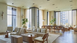 A spacious living room with a large sofa, a coffee table, and a dining area with a table and chairs. There are large windows providing natural light and a view of the city. - Kimpton Shinjuku Tokyo by IHG (Tokyo)