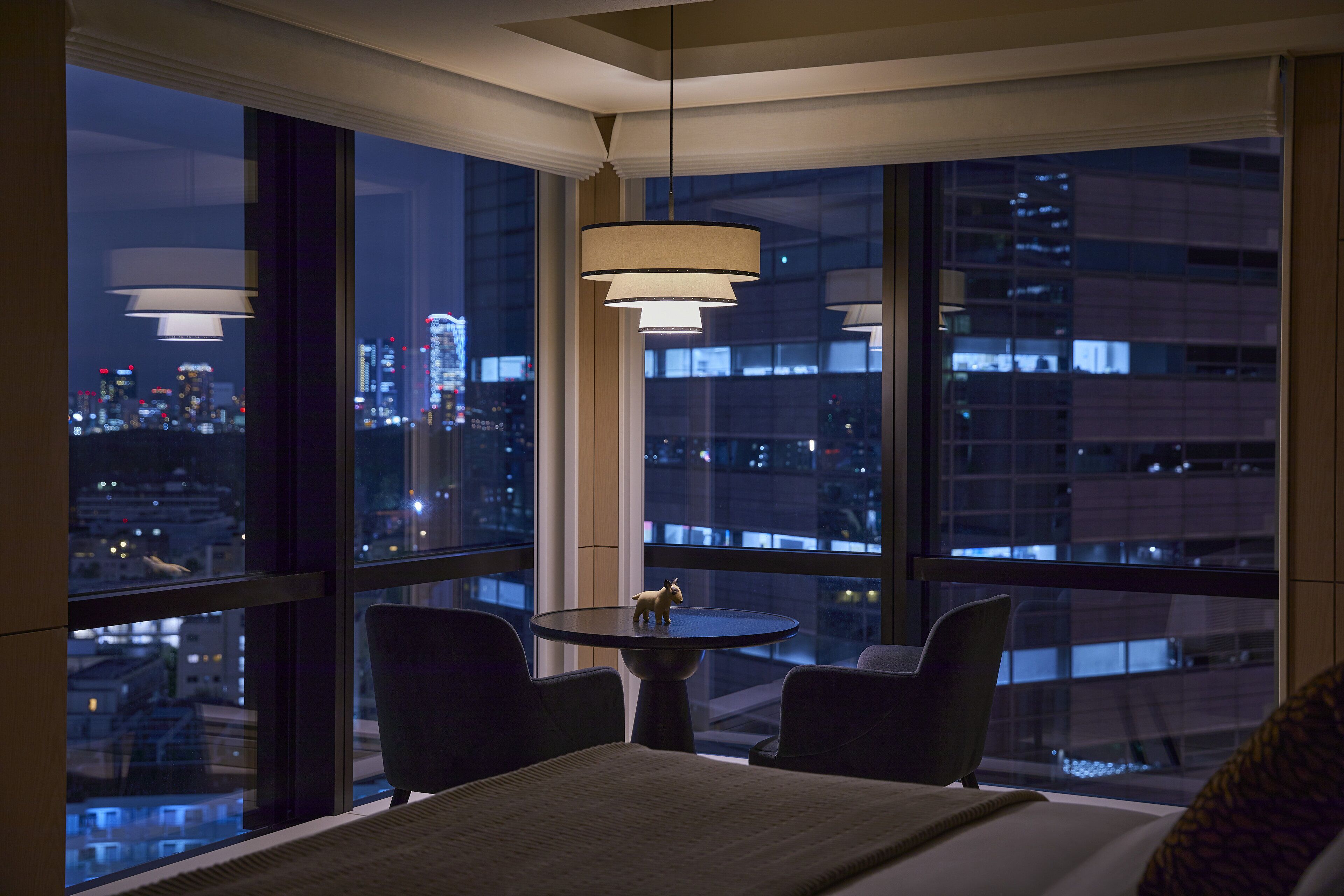 Ein Hotelzimmer mit großem Fenster, einem Bett, einem kleinen Tisch und zwei Stühlen.