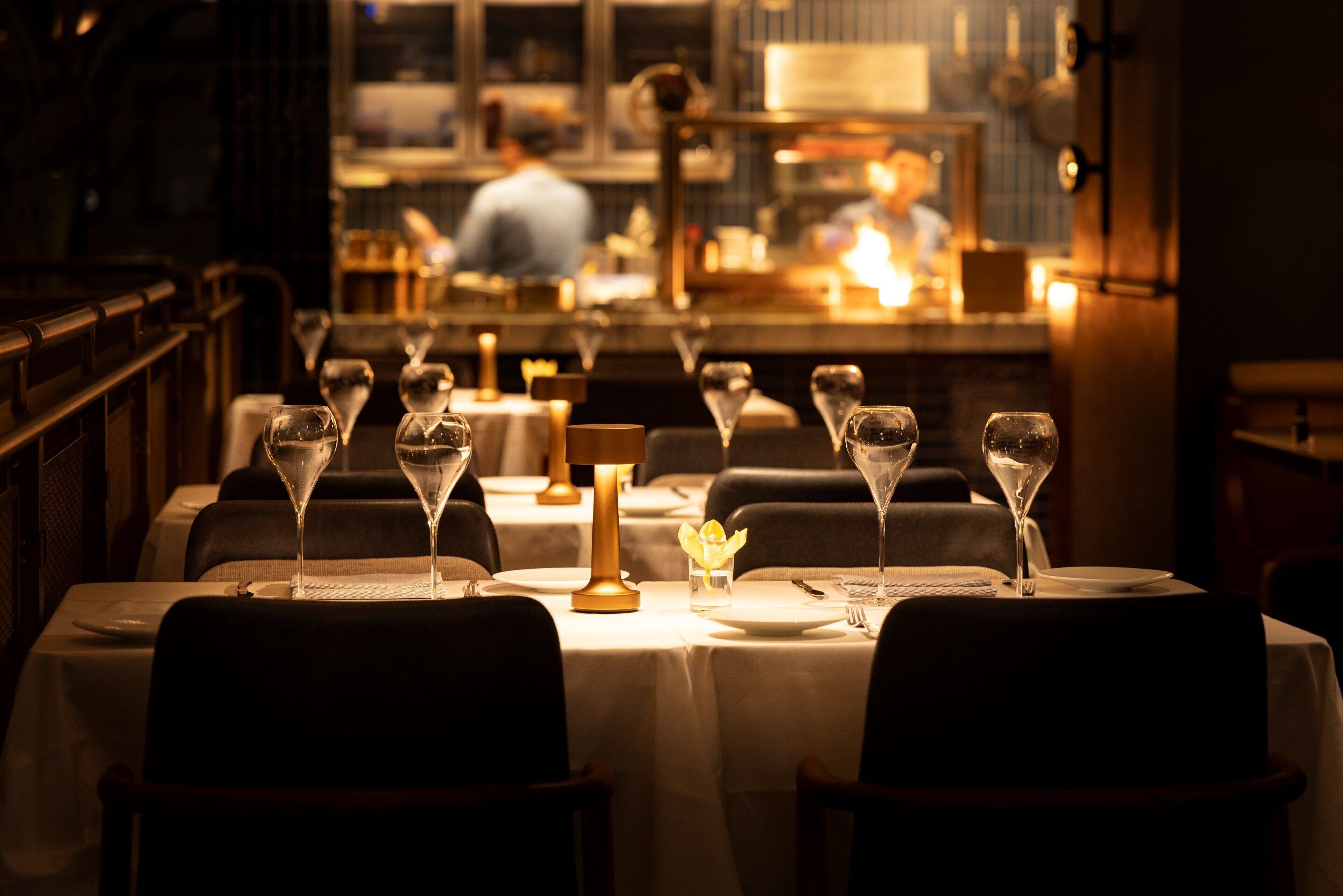 Un restaurante con mesas preparadas para comer, con copas de vino y velas.