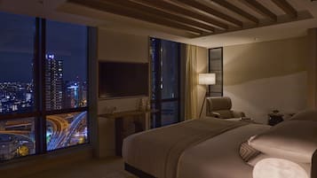 Una habitación de hotel moderna con un gran ventanal, una cama, un escritorio y una silla.