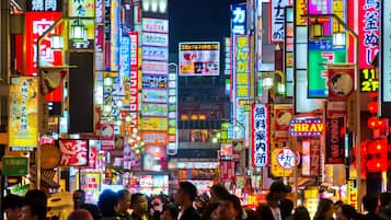 A busy urban street at night with numerous brightly lit signs and advertisements.