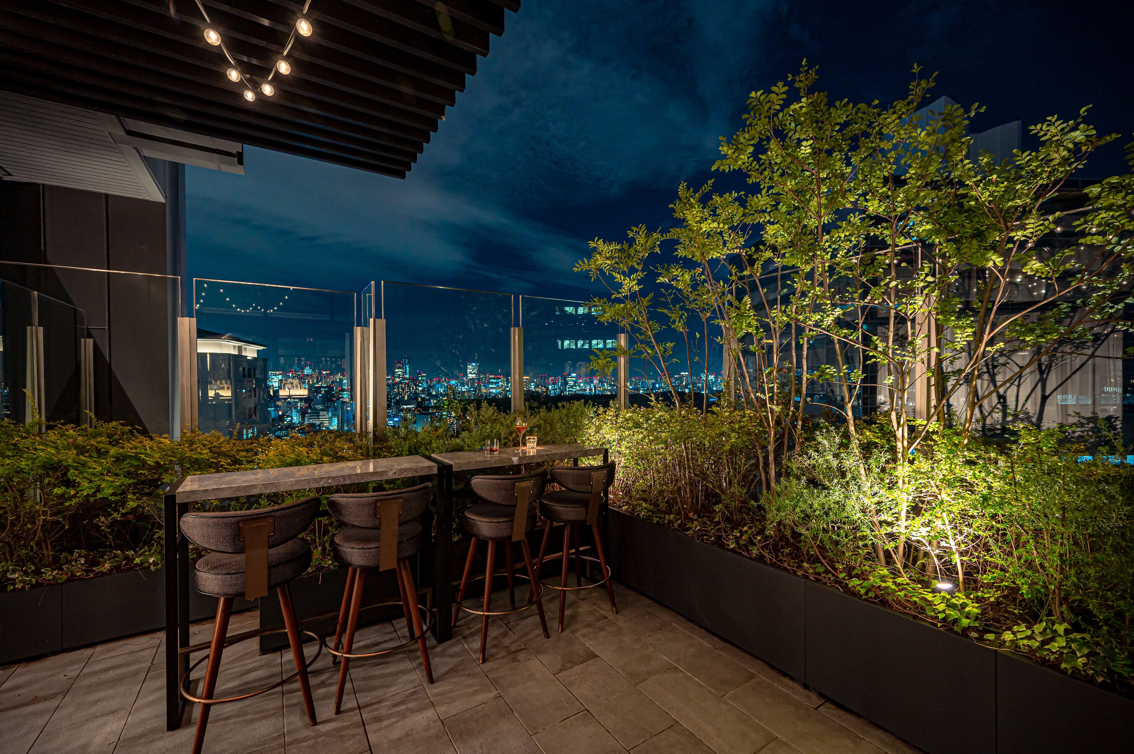 An outdoor bar area with a view of the city at night.
