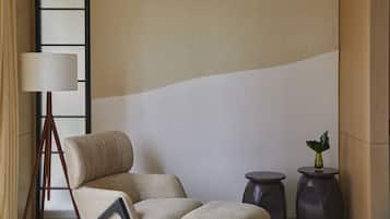 A modern room with a large window, a standing lamp, a sofa, and two small side tables.