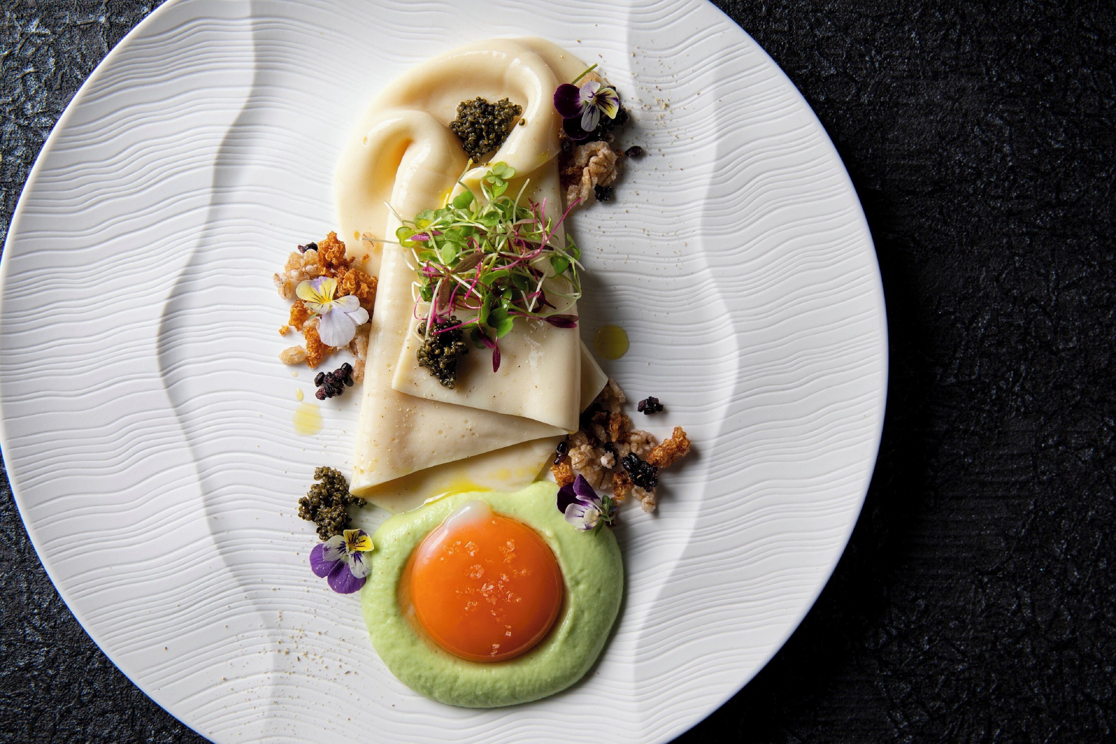 A plate with a food item, possibly a pastry, garnished with greens and a fried egg.