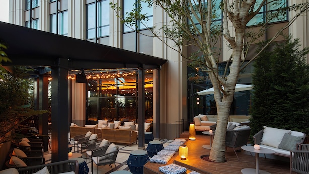 An outdoor seating area with tables, chairs, and a covered section with a view of the interior. - Kimpton Shinjuku Tokyo by IHG (Tokyo)