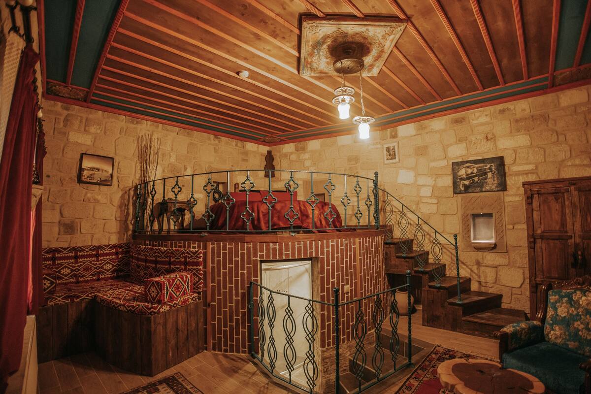 A rustic room with a brick fireplace, wooden bench, and a spiral staircase.