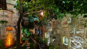 A stone pathway leading through a garden with potted plants and a stone wall with a window. - Vintage Cave House (Nevsehir)