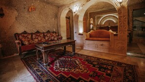 A room with a traditional sofa, a wooden coffee table, and a patterned rug. - Vintage Cave House (Nevsehir)