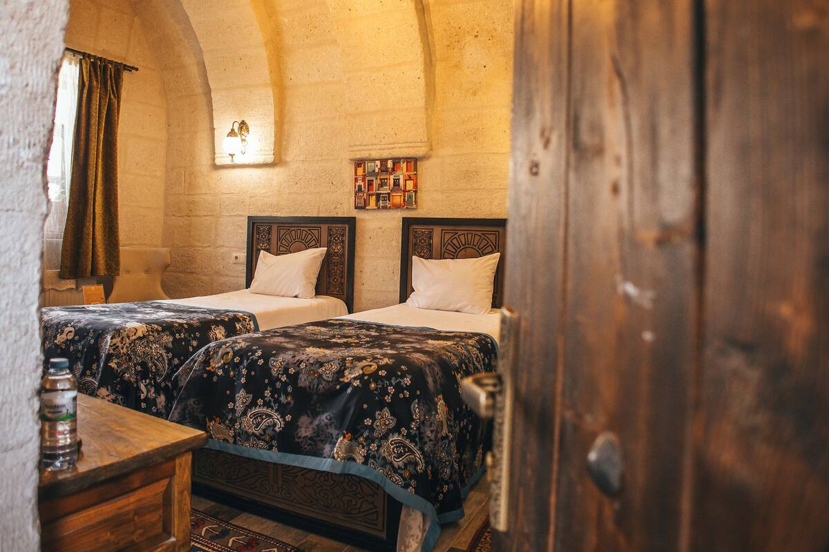 A rustic room with two beds, a wooden table, and a hanging light fixture.