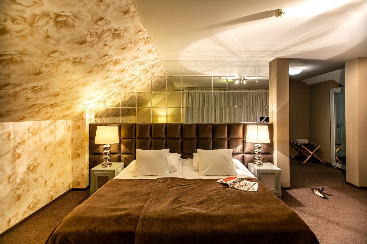 A hotel room with a large bed, two bedside tables, a headboard, and a mirror.