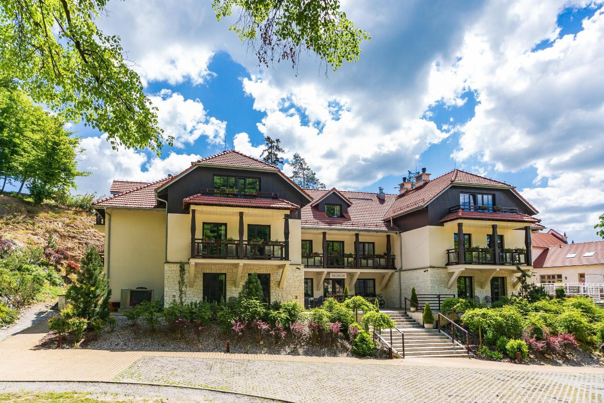 A multi-story hotel with a stone facade, balconies, and a paved driveway.