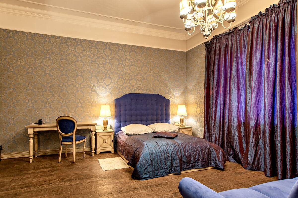 A bedroom with a large bed, a desk, and a chair.