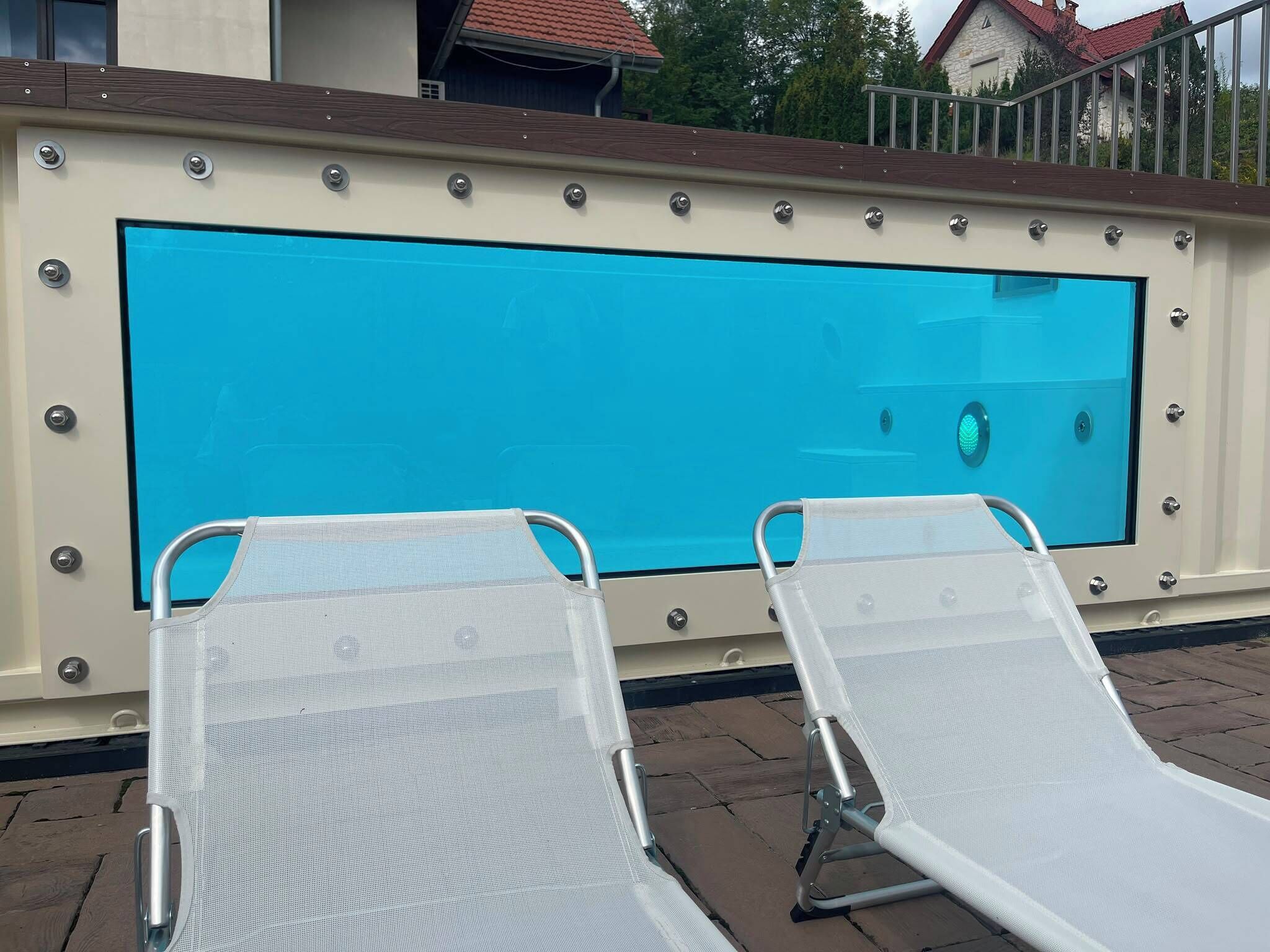 A swimming pool with two lounge chairs and a safety sign.