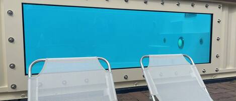 A swimming pool with two lounge chairs and a safety sign.