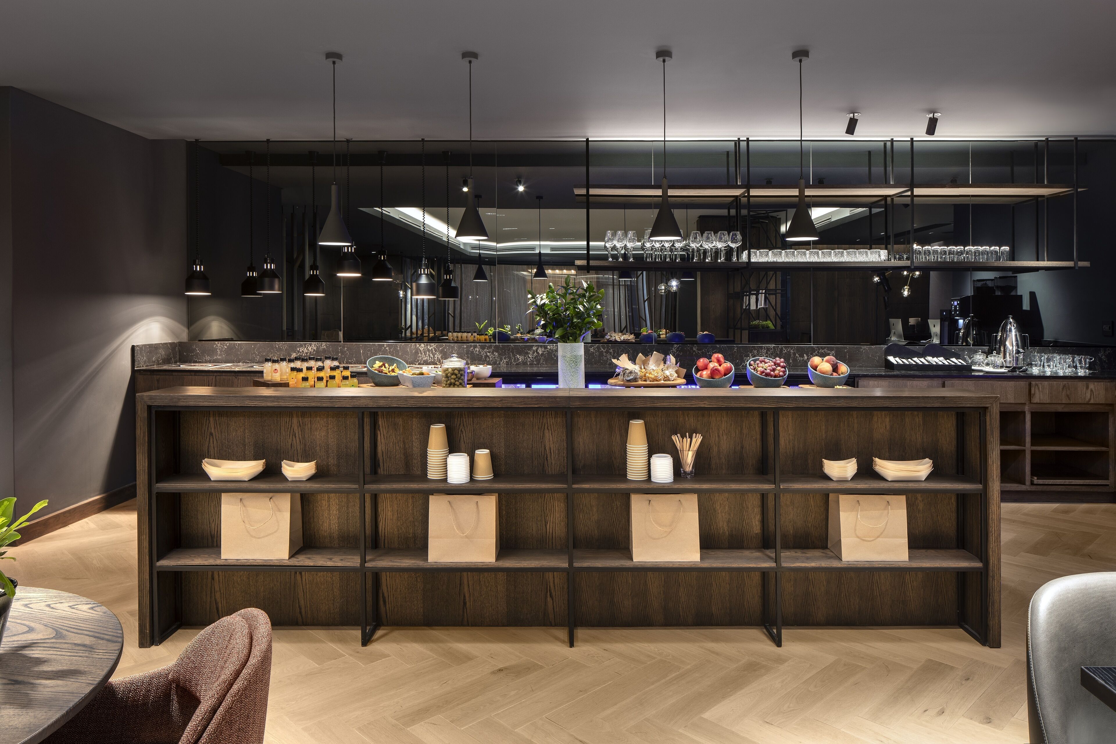 Une cuisine moderne avec des étagères en bois foncé, un plan de travail en marbre et des luminaires suspendus.