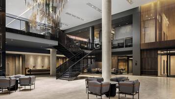 A spacious lobby with a central staircase, seating area, and a modern chandelier.