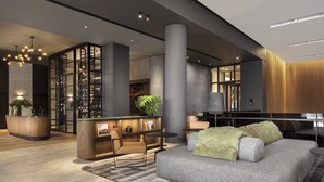 A modern lobby with a reception desk, seating area, and a large plant.