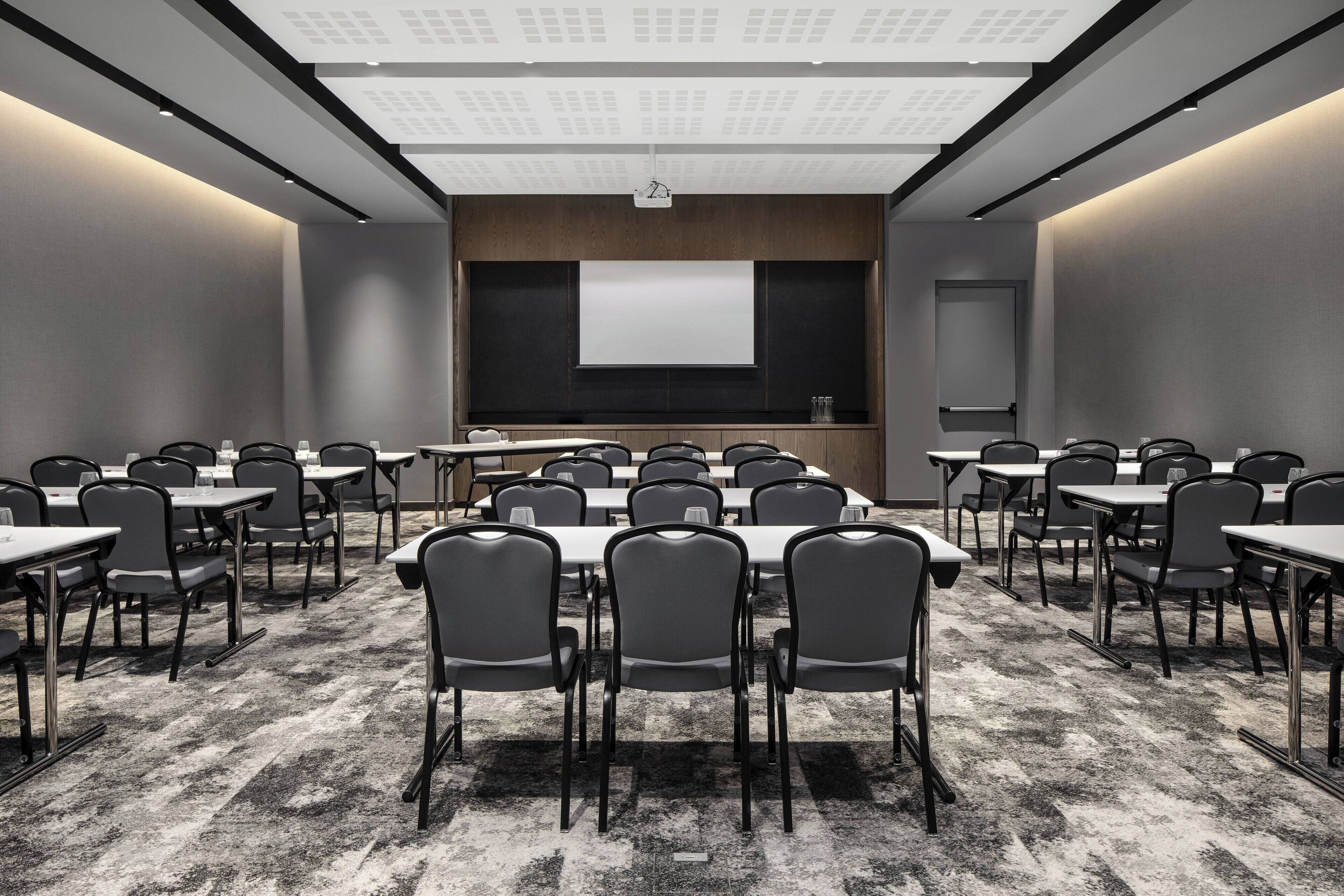A conference room with a large table and chairs, a projector screen, and a whiteboard.