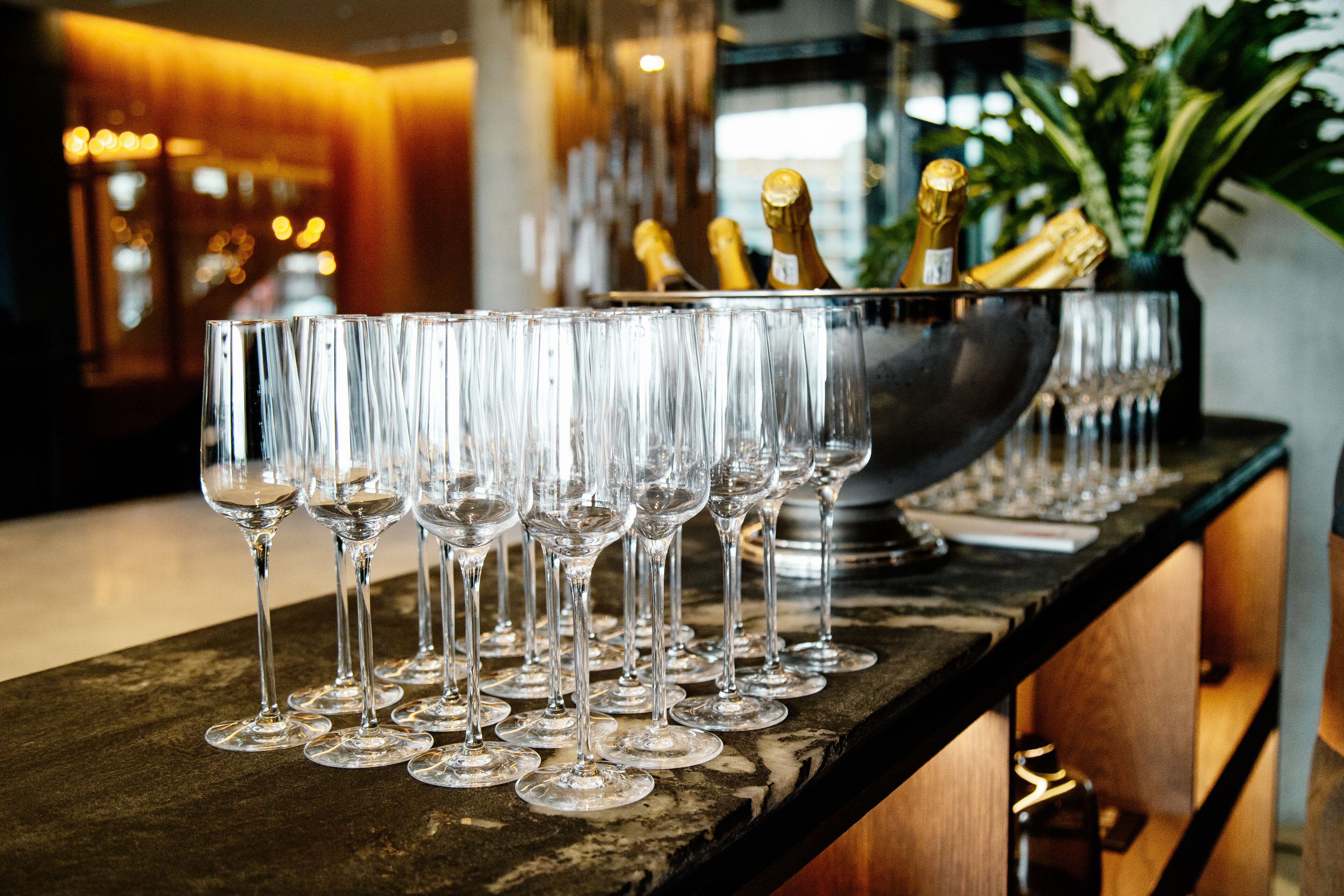 A bar area with a row of empty wine glasses and a bowl containing champagne bottles.