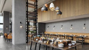 A modern dining area with multiple tables, overhead pendant lighting, and a wooden accent wall.