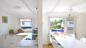 A modern kitchen with white cabinetry, a large window, and a view of a swimming pool.