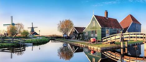 A canal with traditional windmills and wooden houses reflecting in the water.