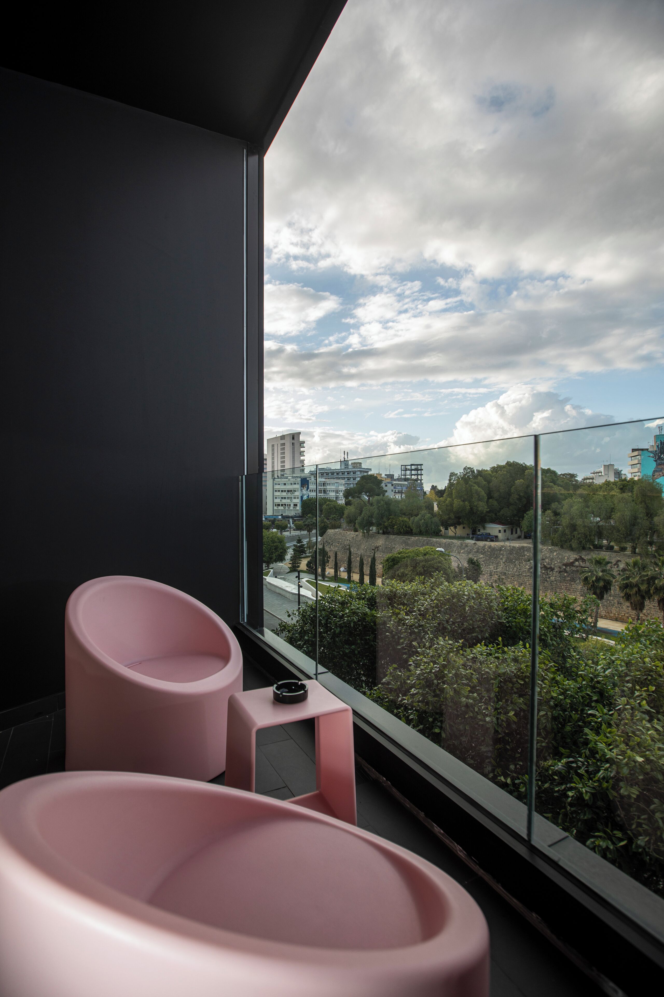 A modern room with a large window, a pink chair, and a small table.