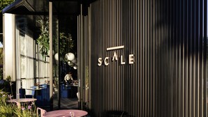 Un edificio moderno con fachada de rayas verticales y la palabra "SCALE" destacada.