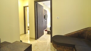 A hotel room with a sofa, a small table, and a door leading to a bathroom. - Hotel Shreesh Kolkata (Kolkata)