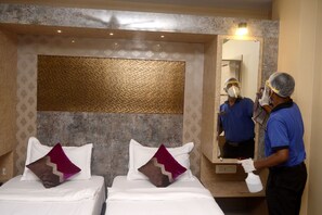 A hotel room with two beds, a large mirror, and a wall with a textured gold panel.