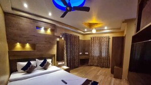 A hotel room with a bed, a ceiling fan, a TV, and a wooden floor. - Hotel Shreesh Kolkata (Kolkata)