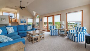 A spacious living room with a blue sofa, striped armchairs, and a wooden coffee table. - Climate Change - Duck, Sea Tern, Oceanside, 280 Yds to Beach, Pool, Hot Tub, Pets OK (Duck)