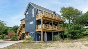 A two-story house with a wooden deck and a staircase leading to the second floor. - Climate Change - Duck, Sea Tern, Oceanside, 280 Yds to Beach, Pool, Hot Tub, Pets OK (Duck)