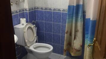 Un baño con inodoro, toallero y cortina de ducha.
