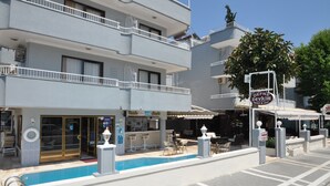 Un hôtel doté d’une piscine, d’un espace extérieur aménagé et d’une enseigne indiquant « DEFNE Zevkim ».