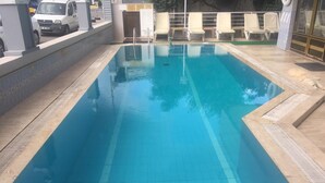 Une piscine rectangulaire à l’eau d’un bleu limpide, entourée d’une terrasse carrelée et d’un petit muret.