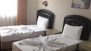 Une chambre d’hôtel avec deux lits, chacun agrémenté d’une serviette blanche soigneusement pliée et d’un oreiller.