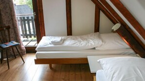 A small, single-bed room with wooden floors and a simple, clean design.