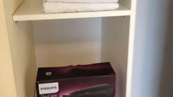 A white shelf with a stack of white towels and a Philips DryCare hair dryer box.