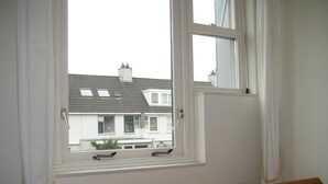 Un dormitorio con ventana, radiador y cama.
