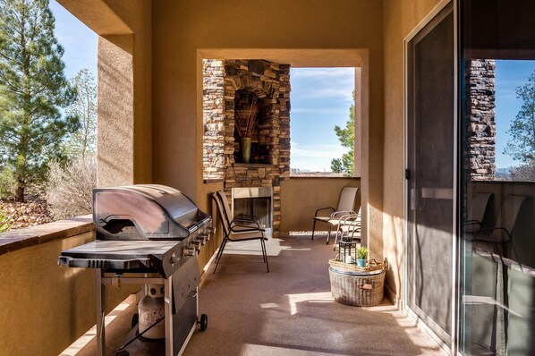Ein Balkon mit Steinkamin, Grill und Gartenmöbeln.