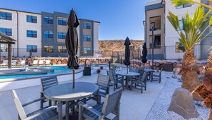 A poolside area with outdoor seating, a swimming pool, and modern buildings in the background.