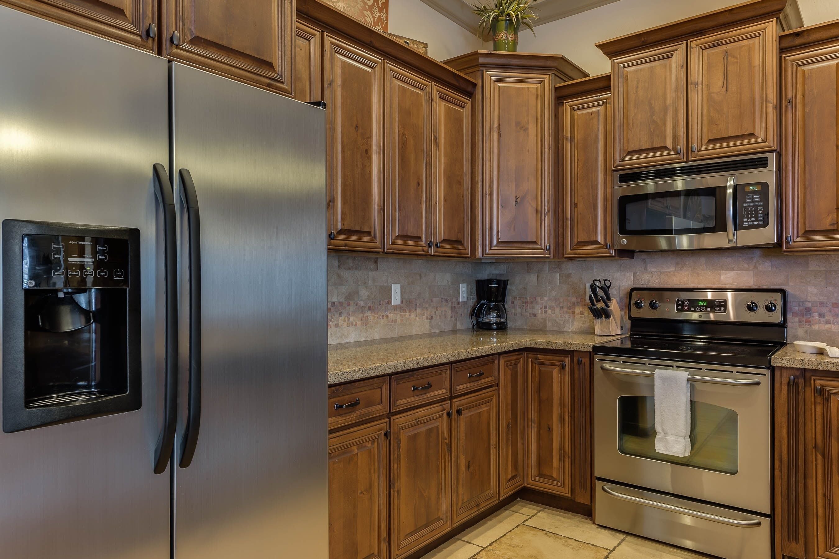 A kitchen with stainless steel appliances, wooden cabinets, and a granite countertop.