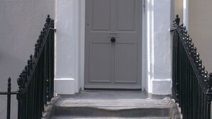 A white front door with a black number plate reading "No 58", flanked by black metal railings and a small window above the door. - Below Deck by Pureserviced (Plymouth)