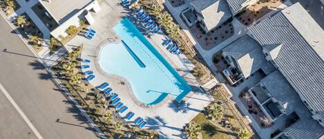 Vista aérea de un hotel con piscina, tumbonas y un área de patio techada.
