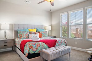 A bedroom with a bed, a nightstand, a bench, and a ceiling fan.