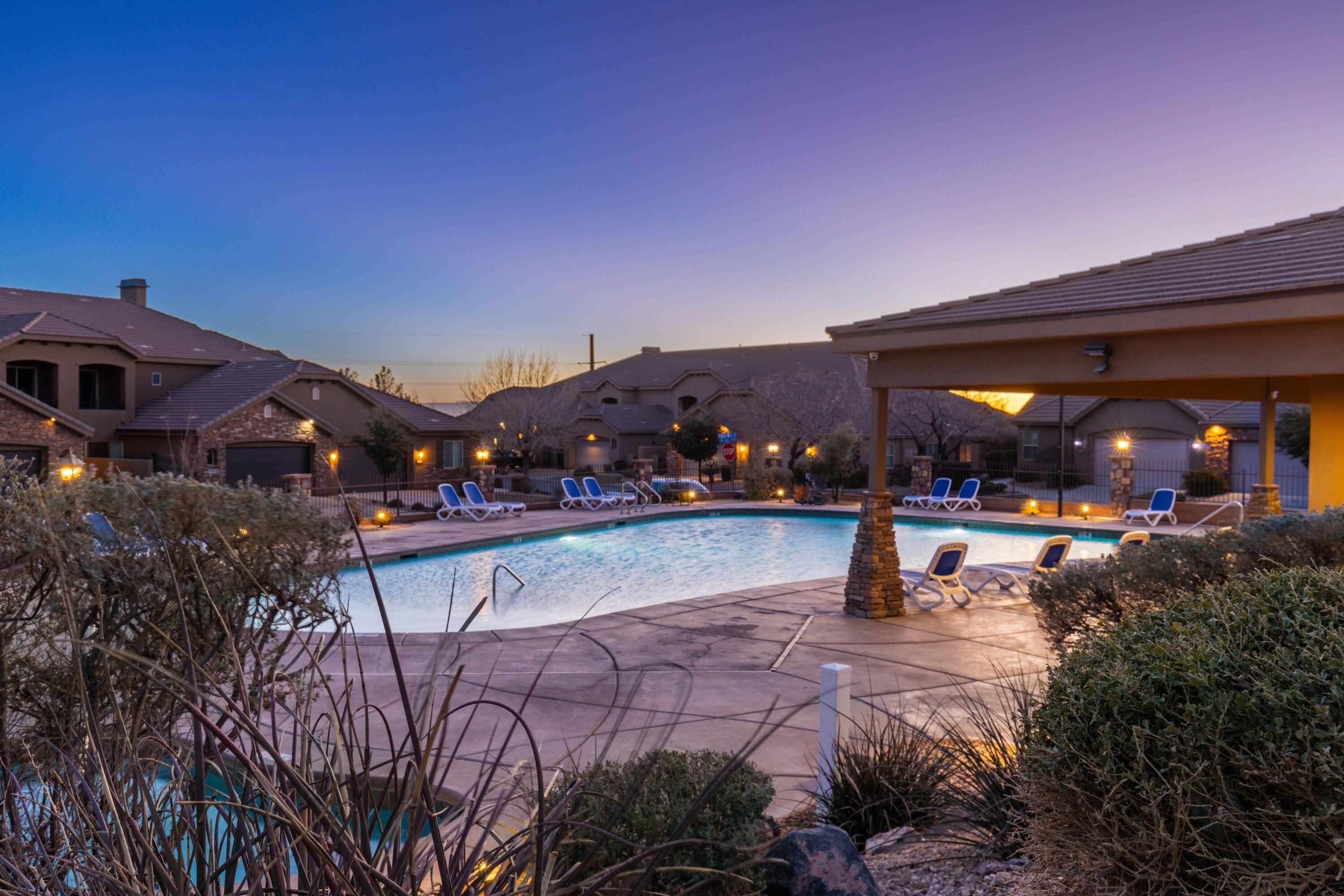 A pool area with lounge chairs and a covered seating area.