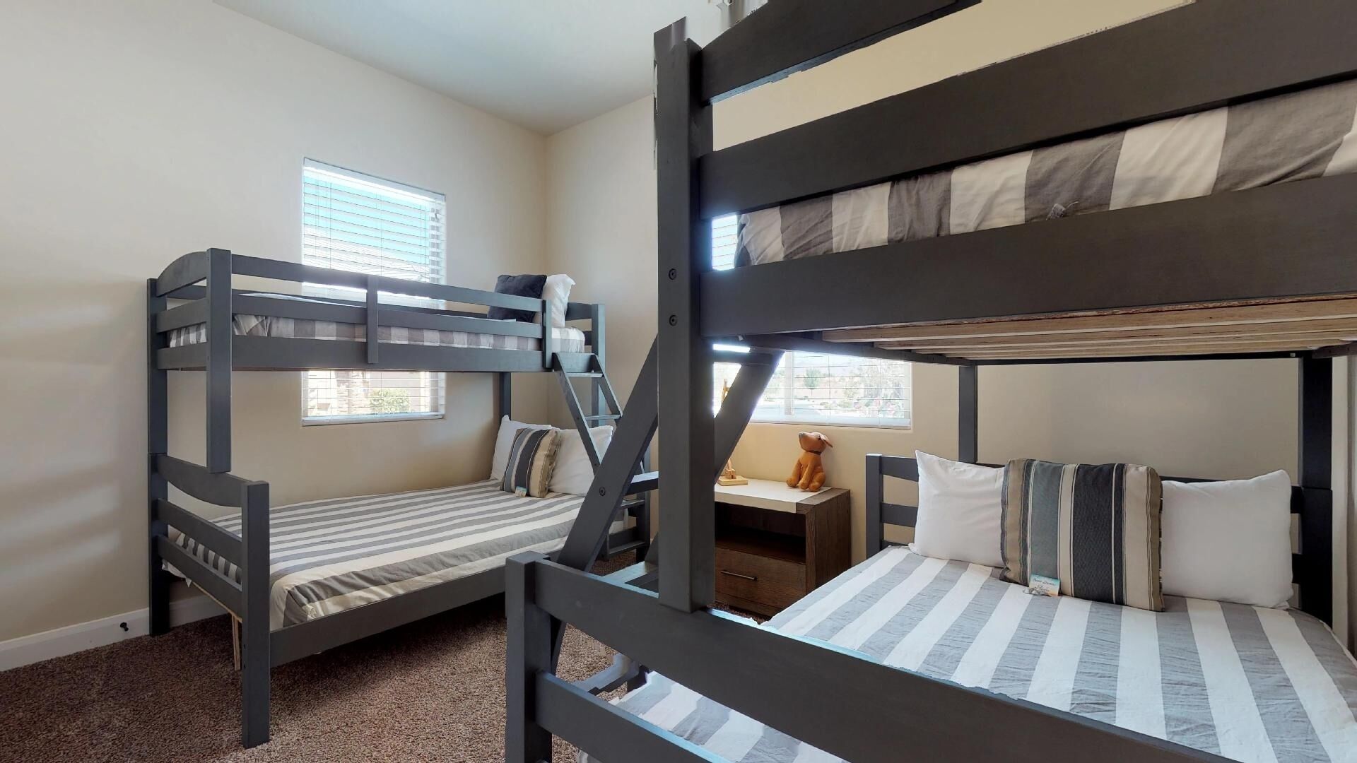 A bunk bed room with two beds, a small desk, and a window.
