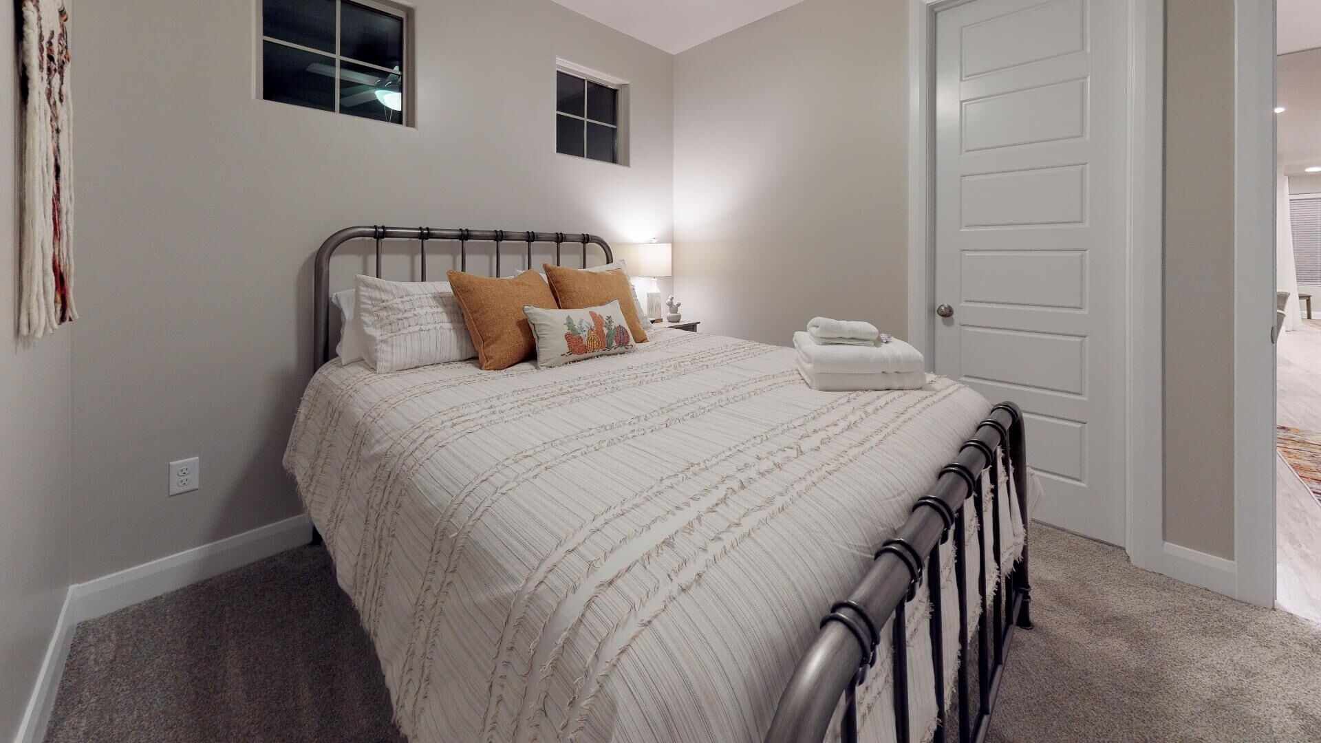A bedroom with a bed, bedside tables, a nightstand, a door, and a window.