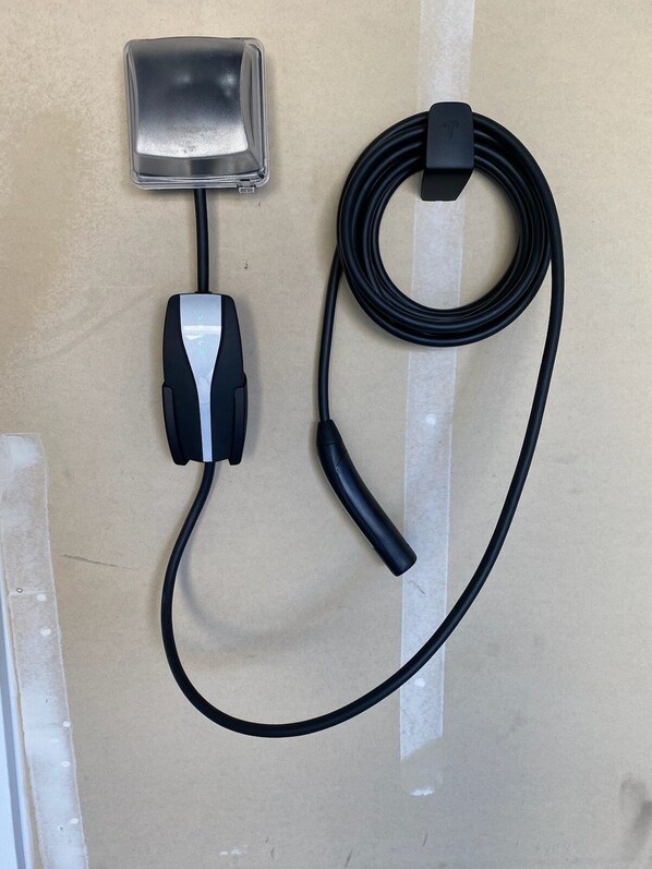 A power strip with a cable and a plug on a beige wall.